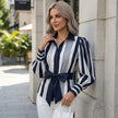 FJØRNA women's summer blouse with striped pattern and puff sleeves, styled for casual wear in a lifestyle setting.