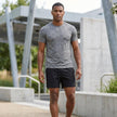 Men's FJØRNA athletic shorts with adjustable waist, pockets, and woven performance fabric, shown in a casual lifestyle setting.