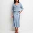 Light blue FJØRNA relaxed V-neck knit top and satin maxi skirt set, featuring a cozy knit top and flowing satin skirt.