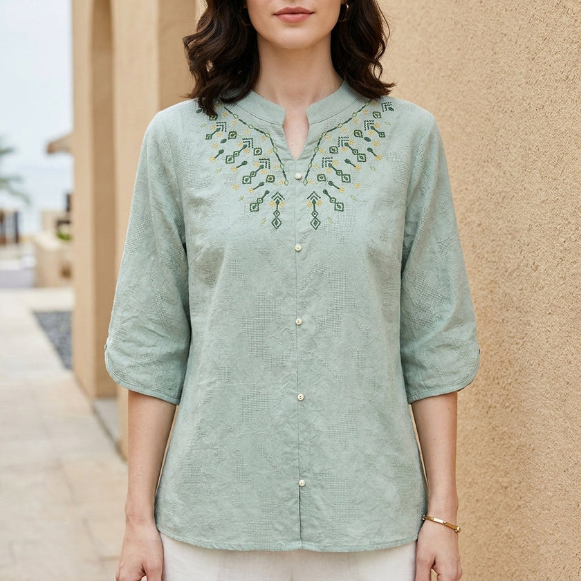 Light blue FJØRNA women's summer denim blouse, flowy and lightweight, shown on a model. Perfect for casual warm weather wear.