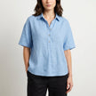 Light blue FJØRNA women's summer blouse, short sleeve denim top, casual and stylish for warm weather.