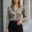 Light gray women's summer blouse with long sleeves and floral print by FJØRNA, shown hanging on a hanger.