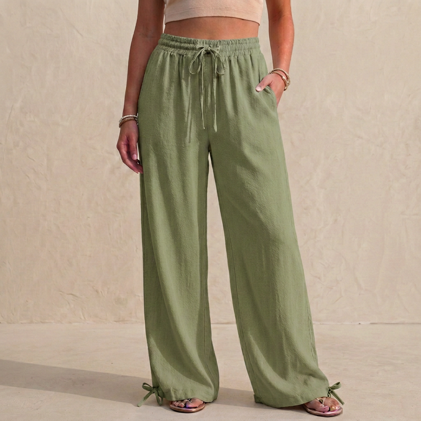 Light green women's summer trousers by FJØRNA with linen fabric, pockets, and drawstring waist, perfect for warm weather wear.