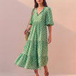 Light green FJØRNA midi dress with V-neck, puff sleeves, and tiered skirt, flowing and elegant for versatile occasions.