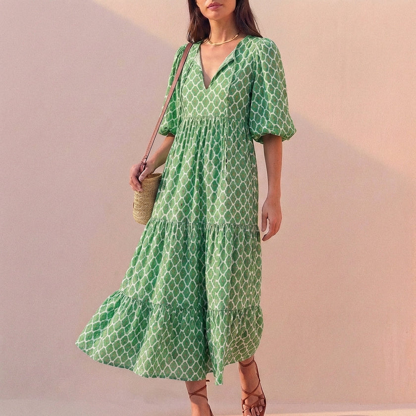 Light green FJØRNA midi dress with V-neck, puff sleeves, and tiered skirt, flowing and elegant for versatile occasions.