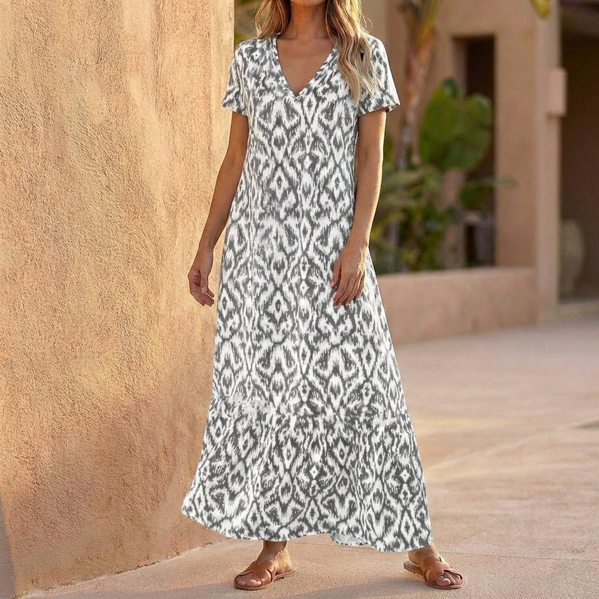 Light grey FJØRNA V-neck maxi dress with ruffled hem, flowing fabric, and elegant design, perfect for casual or formal wear.