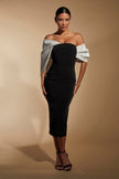 FJØRNA Ava off-shoulder midi dress in white with sculpted monochrome details, shown on a model against a neutral background.
