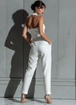 Ivory cotton-linen women's jumpsuit with V-neck, cinched waist, and wide-leg pants by FJØRNA, shown on a model.