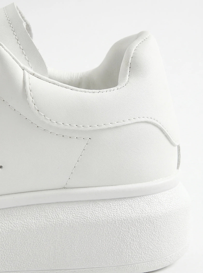 Close-up of FJØRNA men's white lace-up trainers showing minimalist design and detailed stitching on the shoes.