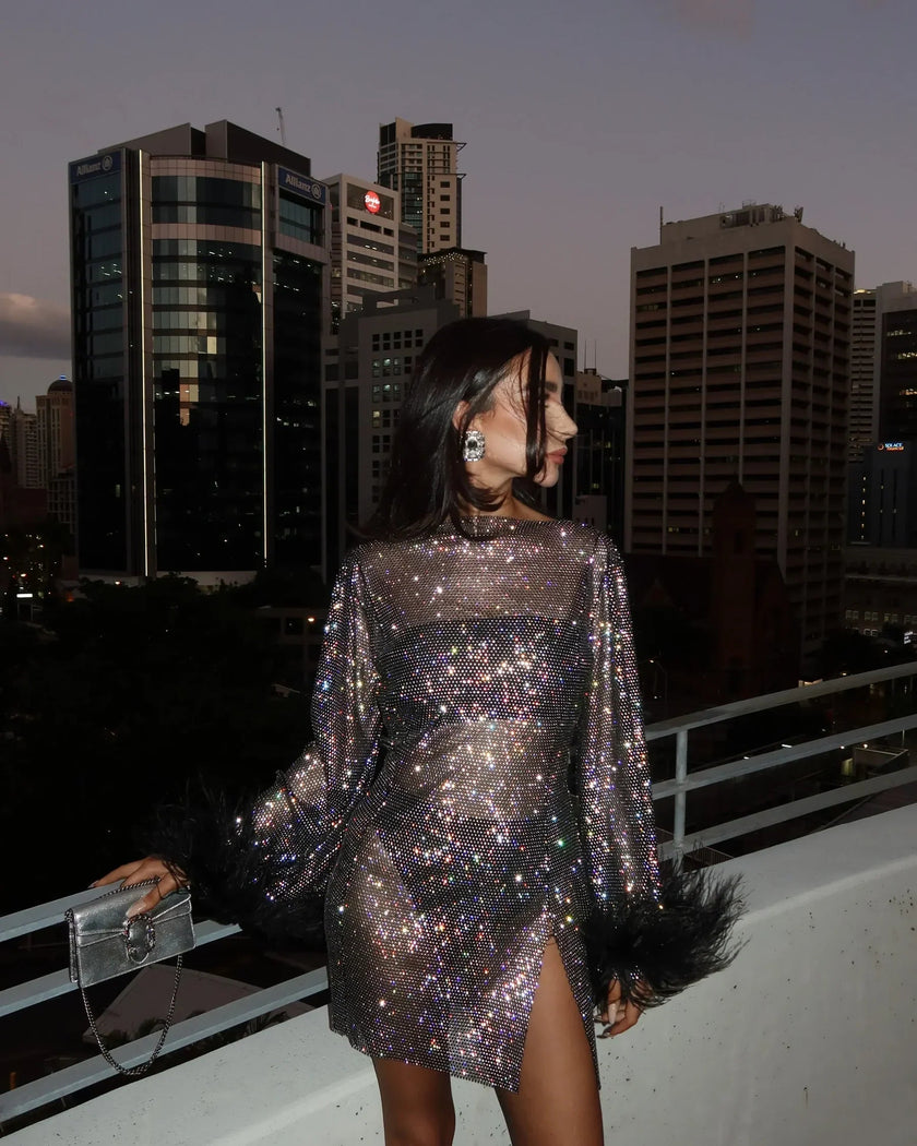 FJØRNA sequin feather mini dress with long sleeves, sheer details, fitted silhouette, and feather cuffs for women’s party wear