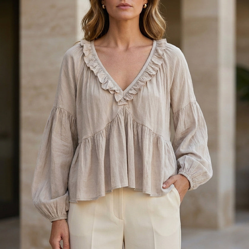 FJØRNA women's summer blouse with V-neck, long sleeves, denim fabric, and ruffle details, in a soft milky white color.