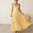 FJØRNA Eileen satin ruched bodice sleeveless maxi dress with pleated skirt, worn by a model showcasing elegant evening wear style.