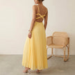 FJØRNA Eileen satin ruched bodice sleeveless maxi dress with pleated skirt worn by model, elegant evening gown with flowing design.