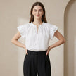 FJØRNA summer blouse for women with cap sleeves and ruffle details, modeled in a light, breezy top for warm weather.