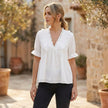 Women’s relaxed peplum blouse by FJØRNA featuring a ruffled V-neck and tiered hem, worn by a model.