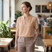 FJØRNA women's summer blouse with V-neck, short sleeves, flowy fabric, worn by a model in a casual outdoor setting.