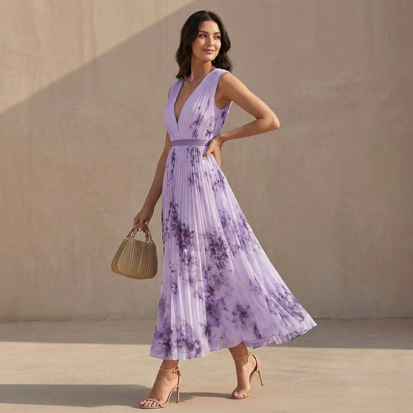 Model wearing FJØRNA pleated A-line maxi dress with V-neck and balloon sleeves, flowing fabric and elegant silhouette.