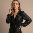 FJØRNA women's summer blouse with V-neck and long sleeves featuring sequin embellishments, worn by a model.