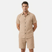 Men's beige linen two-piece set by FJØRNA, featuring a buttoned short sleeve shirt and matching shorts worn by a model.