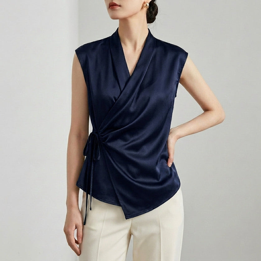 Navy blue women's satin summer blouse with V-neck and sleeveless design, from FJØRNA, styled on a hanger.