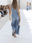 Light blue denim sleeveless jumpsuit with raw edges and wide-leg design by FJØRNA, shown on a model.