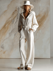 White corduroy hooded jumpsuit by FJØRNA featuring a zip-front and long sleeves, styled with a hood and relaxed fit.
