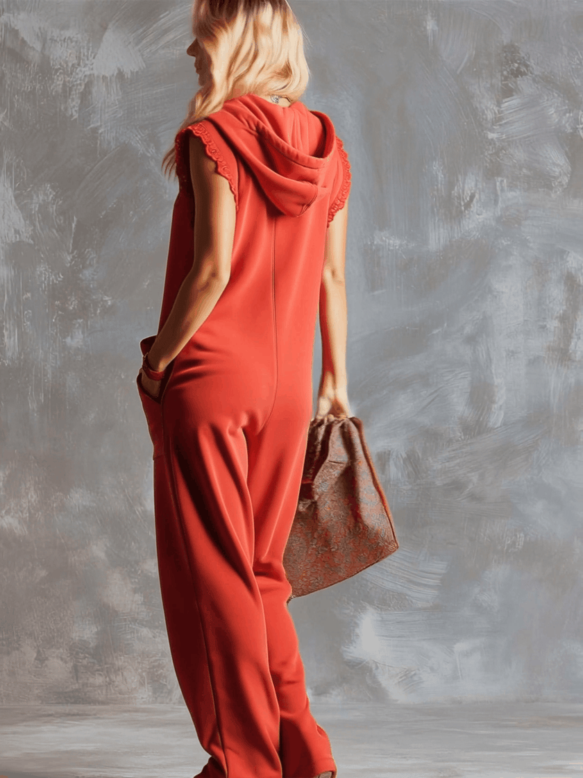 Raspberry red cotton hooded zip-front jumpsuit by FJØRNA featuring a relaxed fit and front zipper, shown on a model.