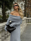 White FJØRNA off-shoulder fit knitted maxi dress displayed on a hanger with a relaxed, flowing design and long sleeves.