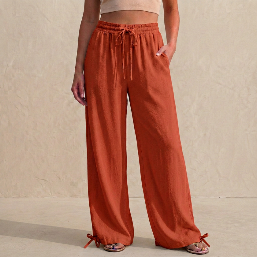 Orange-red women's summer trousers by FJØRNA with linen fabric, pockets, and drawstring waist, perfect for casual warm-weather wear.