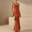 Orange FJØRNA slim fit sleeveless maxi dress with a cowl neck, showcasing its elegant flowy style and fitted silhouette.