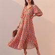 Orange FJØRNA midi dress with V-neck, puff sleeves, and tiered skirt, flowing and elegant for a stylish look.