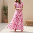 Pink FJØRNA A-line maxi dress with V-neck and flutter sleeves, flowing fabric and elegant design perfect for summer.