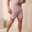 Pink FJØRNA Jess quick-dry relaxed-fit men's swim shorts with side pockets and slit hems, suitable for beach or poolside wear.