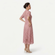 Side profile of FJØRNA women's pink lace midi dress with high neck, elegant silhouette, and refined cutwork detail.