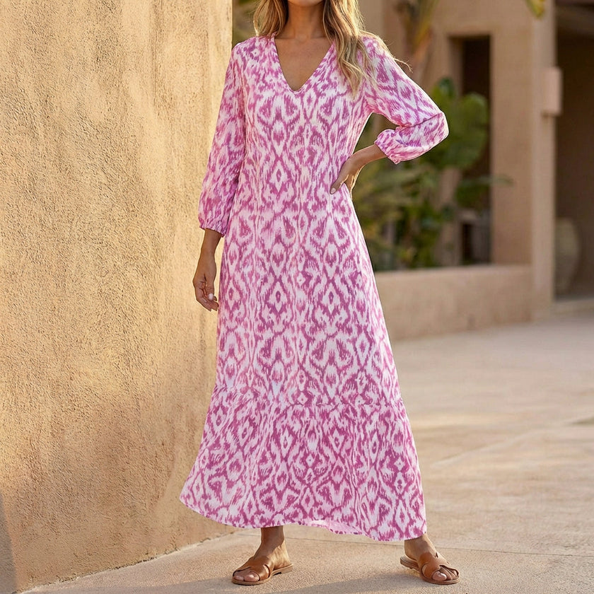 Pink FJØRNA V-neck maxi dress with ruffled hem, flowing fabric, and sleeveless design, perfect for elegant summer occasions.