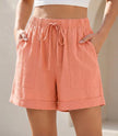 Pink women's summer linen shorts with pockets and drawstring waist by FJØRNA, perfect for casual warm-weather wear.