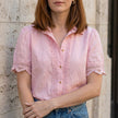 Pink FJØRNA women's summer blouse with V-neck, short sleeves, and lace detailing, perfect for warm-weather stylish wear.