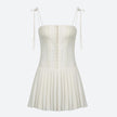 FJØRNA white pleated corset mini dress with structured bodice and flared skirt, perfect for stylish occasion wear.