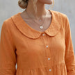 FJØRNA women's relaxed Peter Pan collar shirt with peplum waist, featuring soft fabric and feminine design, worn by a model.