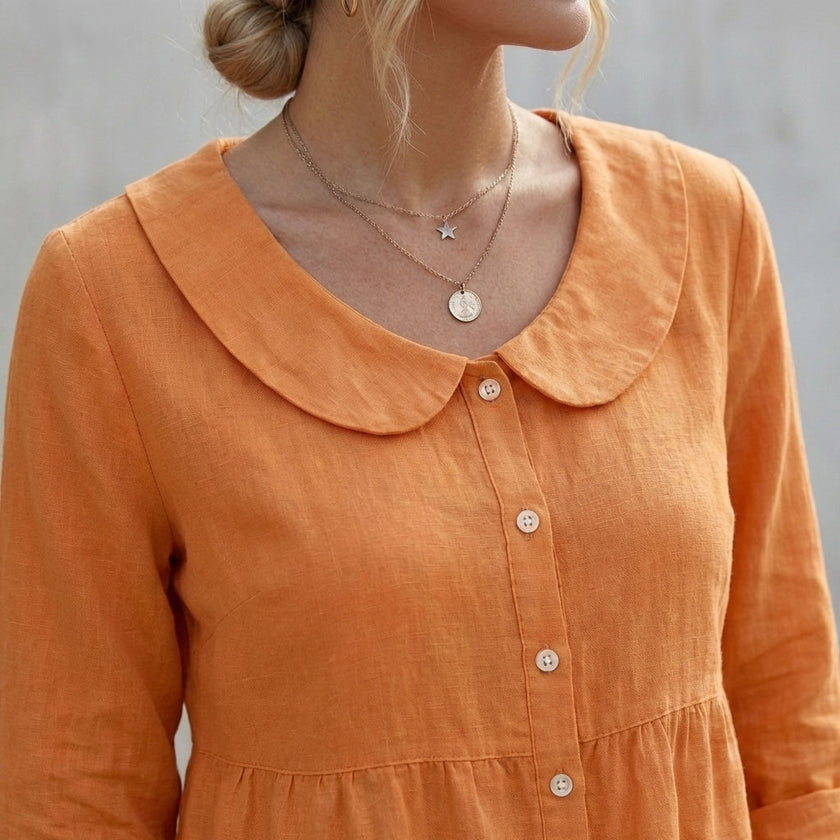FJØRNA women's relaxed Peter Pan collar shirt with peplum waist, featuring soft fabric and feminine design, worn by a model.