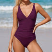 Purple FJØRNA summer one-piece swimsuit for women with V-neck and ruched design, featuring a flattering fit and vibrant color.