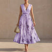 Purple FJØRNA pleated A-line maxi dress with V-neck and balloon sleeves, flowing and elegant on a model.