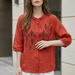 Red women's summer blouse by FJØRNA with geometric pattern and button-front design, shown on a hanger.