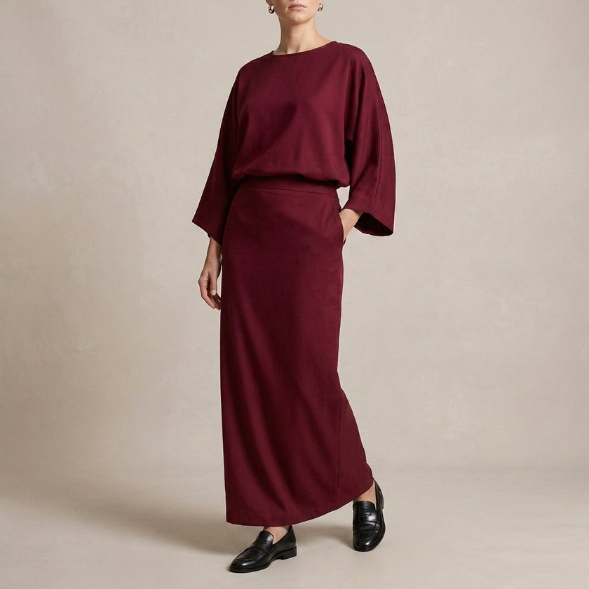 Red two-piece woven skirt suit by FJØRNA featuring textured fabric, draped high-waist silhouette, perfect for elegant occasions.