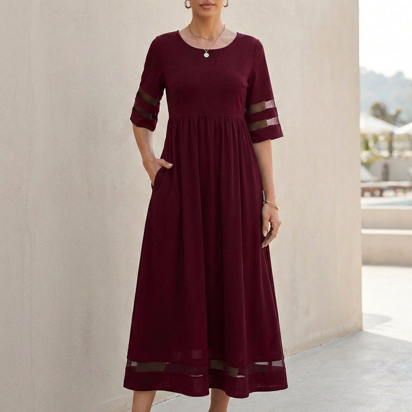 Red FJØRNA A-line maxi dress with mesh panels and pockets, flowing design perfect for casual or formal wear.