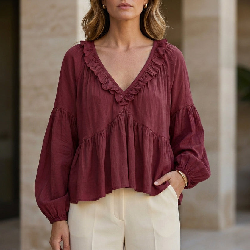 Red FJØRNA women's summer blouse with v-neck, long sleeves, denim fabric, and ruffle details, styled as a casual top.