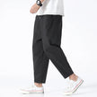 FJØRNA cropped linen trousers in indigo color, featuring a relaxed fit and lightweight fabric, shown on a model.