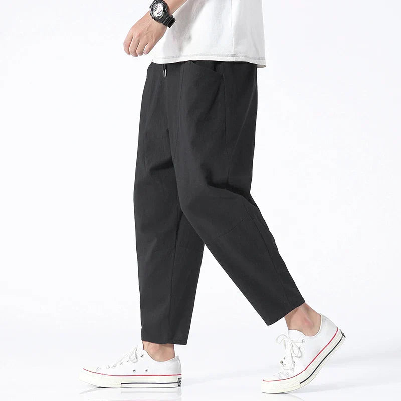 FJØRNA cropped linen trousers in indigo color, featuring a relaxed fit and lightweight fabric, shown on a model.