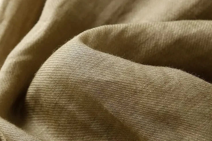 FJØRNA women's linen tapered trousers with a relaxed fit, shown in a natural beige color, styled for casual wear.