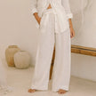 FJØRNA linen wide-leg trousers for women with elastic waistband and ruffle detail, shown in a relaxed fit.
